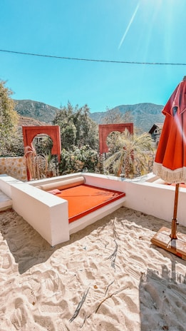 A cozy outdoor rattan daybed with plush cushions nestled under a leafy tree.