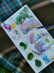 Close-up of a color palette featuring black, green, brown, and gray tones arranged artistically.