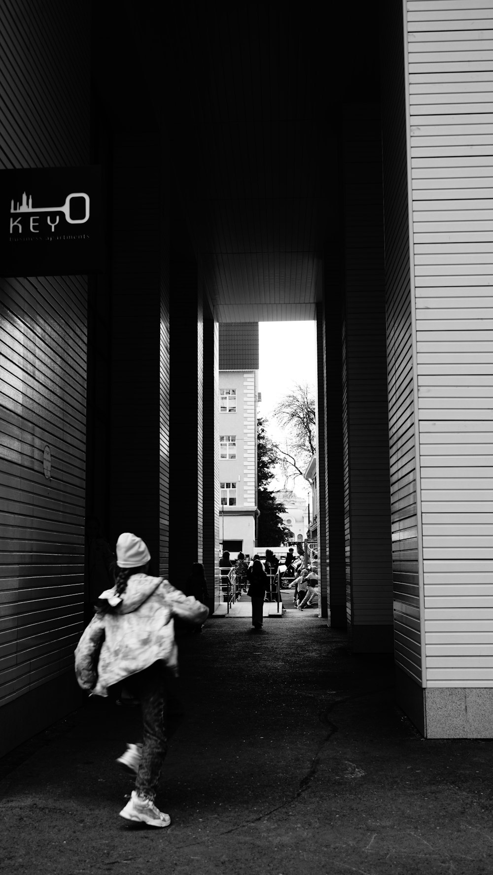 a black and white photo of a person walking down a hallway