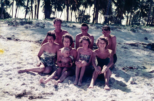 a group of people sitting on top of a sandy beach