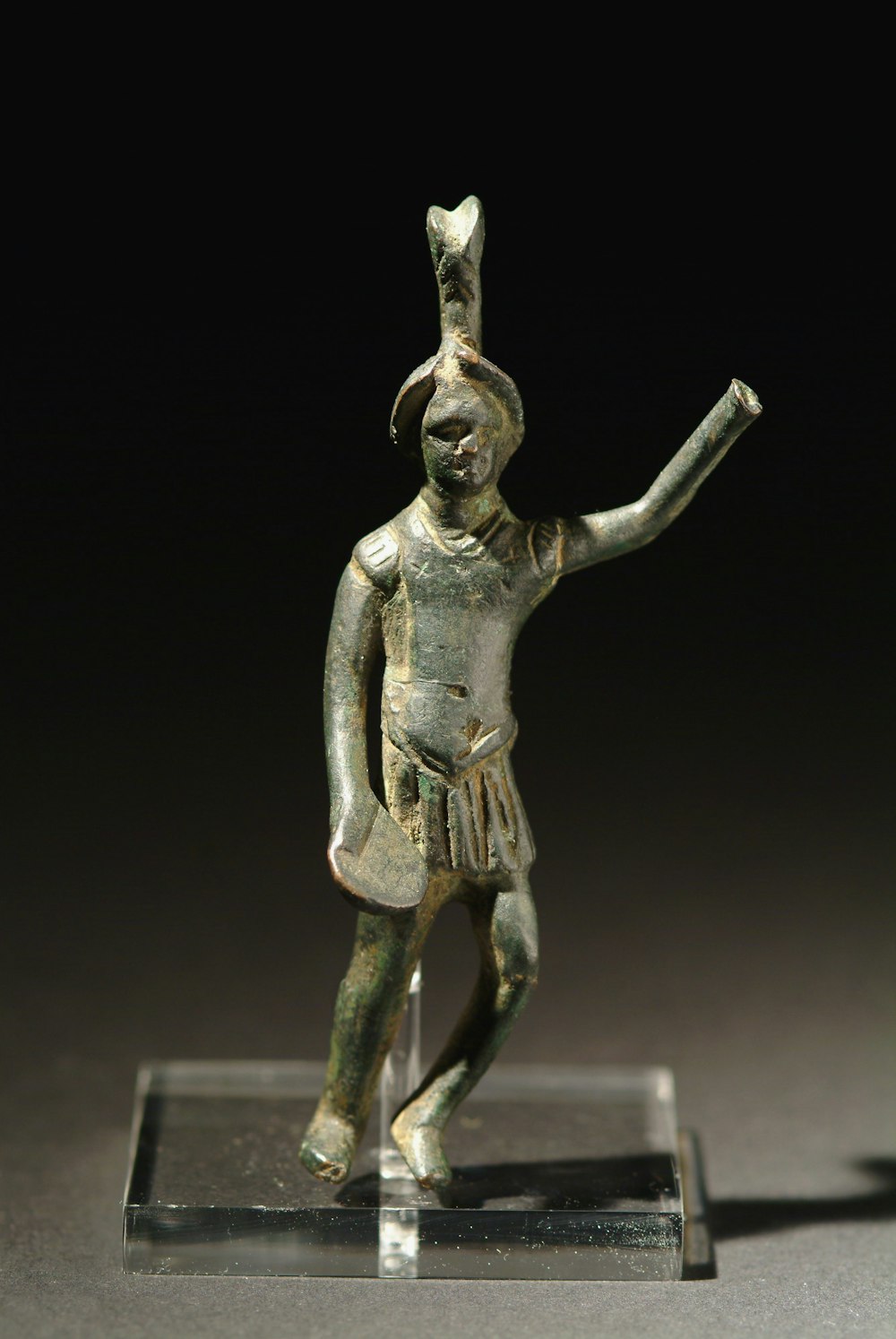 a bronze figurine of a man holding a sword