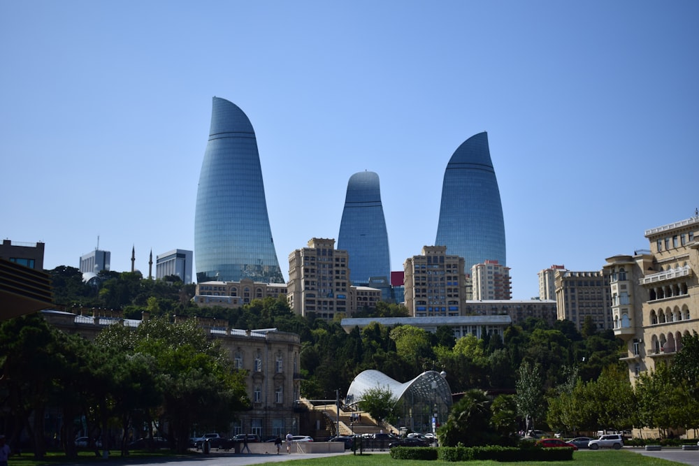 a group of tall buildings sitting next to a lush green park