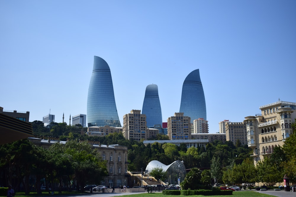 a group of tall buildings sitting next to a lush green park