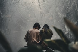 a man and a woman sitting on a bench looking at a waterfall