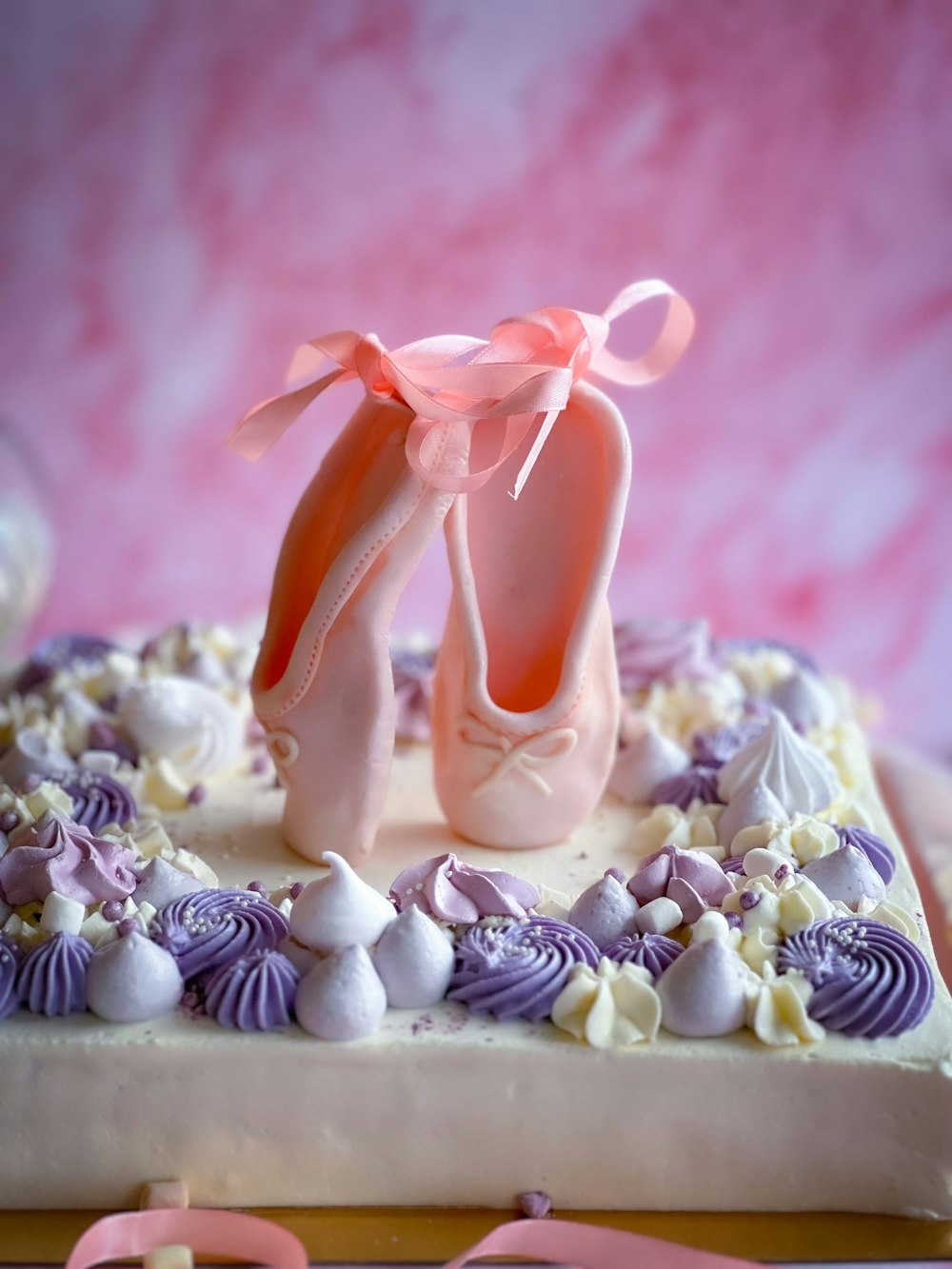 Un pastel decorado con un par de zapatos de ballet y conchas marinas