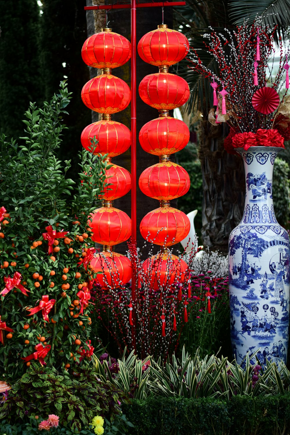 a blue and white vase with red flowers and red lanterns