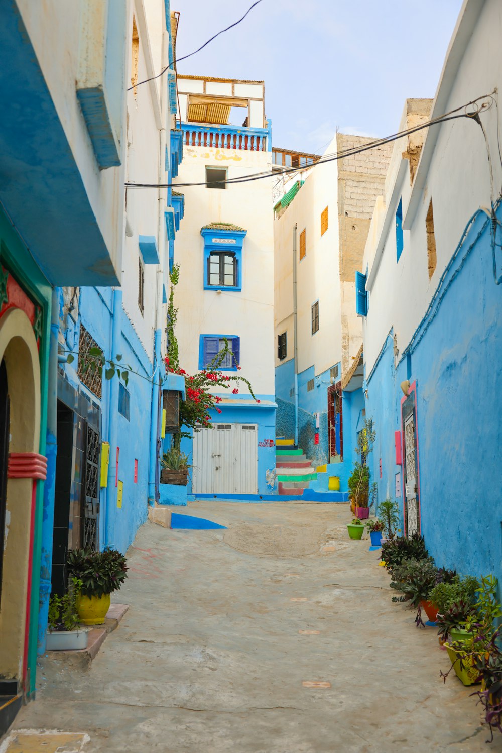 a narrow street with blue buildings and a white door