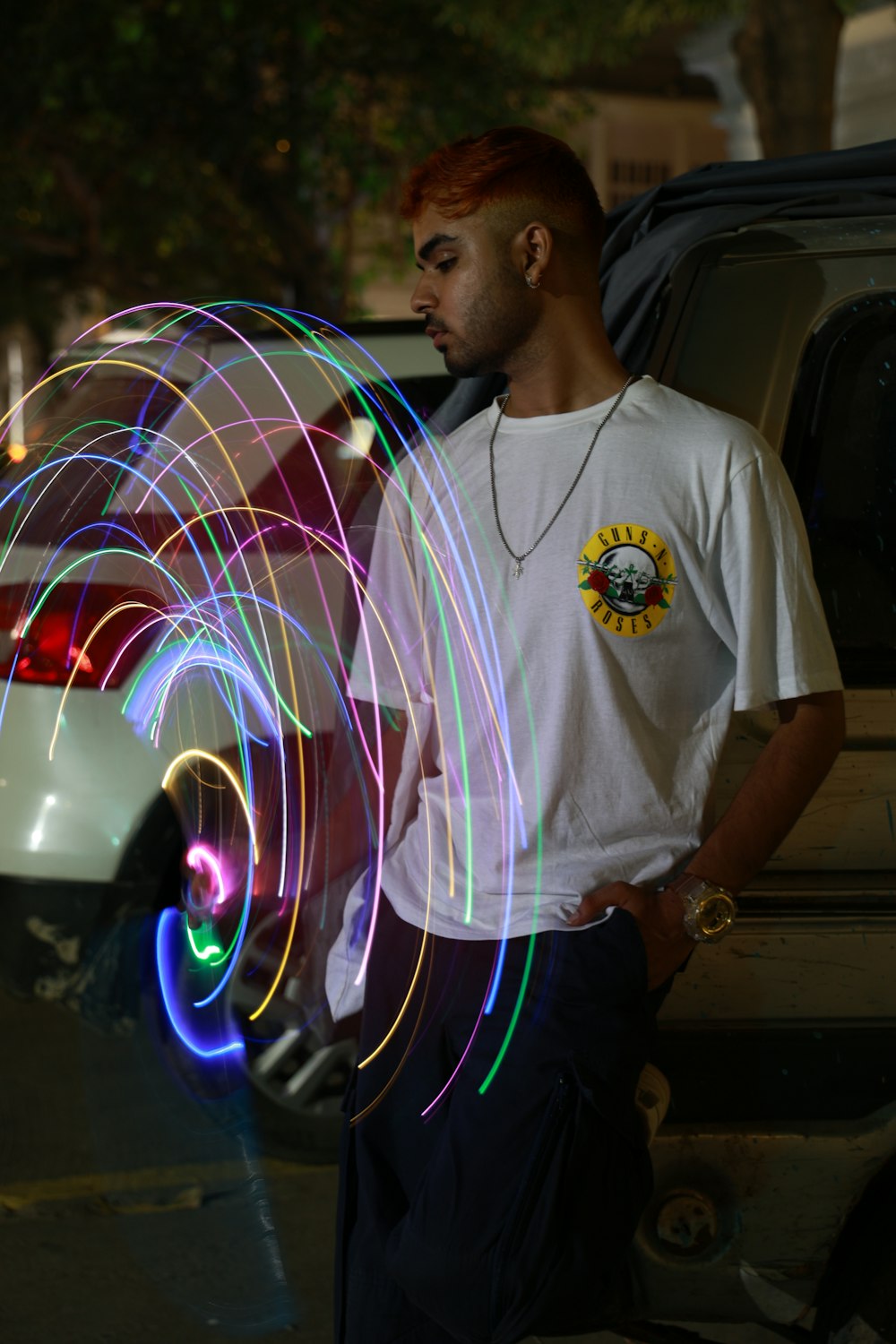 a man standing in front of a car holding a skateboard