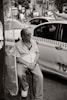 a man sitting on a stool in front of a taxi cab