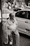 a man sitting on a stool in front of a taxi cab