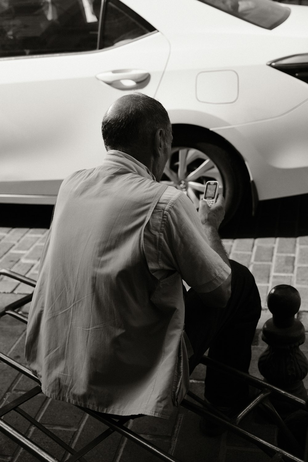 a man sitting next to a parked white car