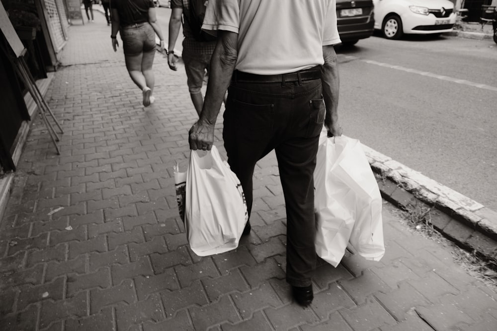 a man walking down a street holding two bags