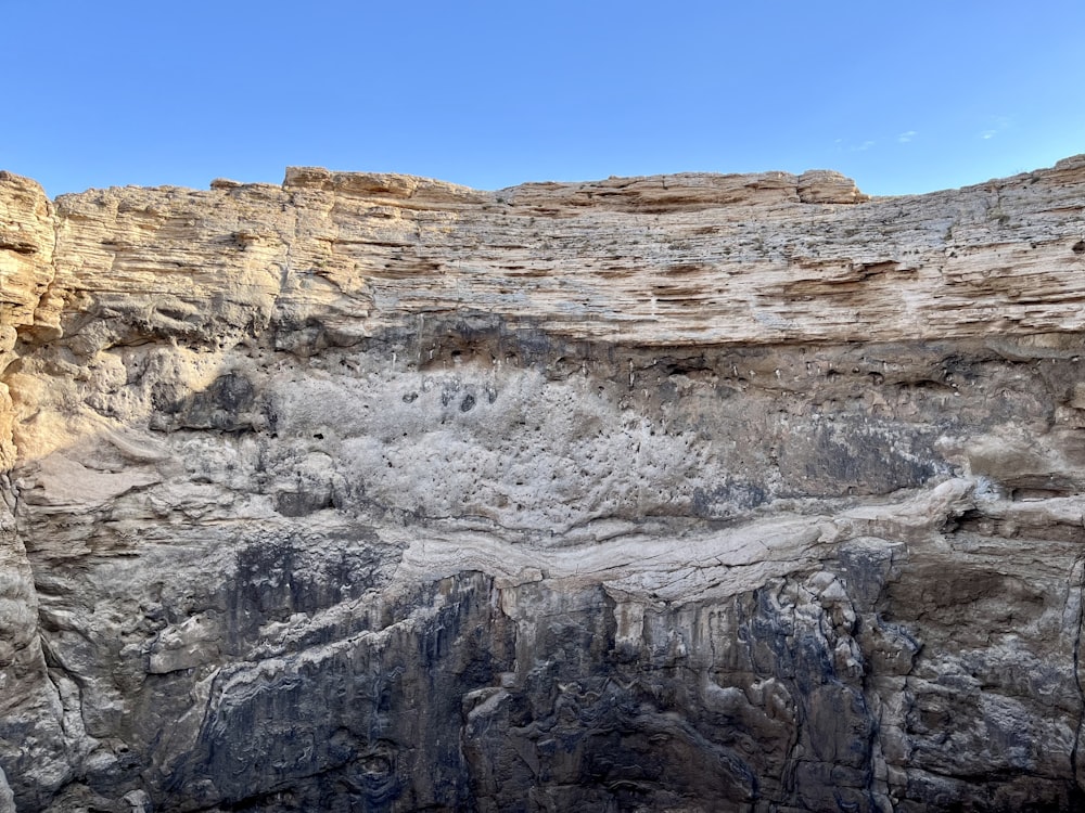 a rocky cliff face with a blue sky in the background