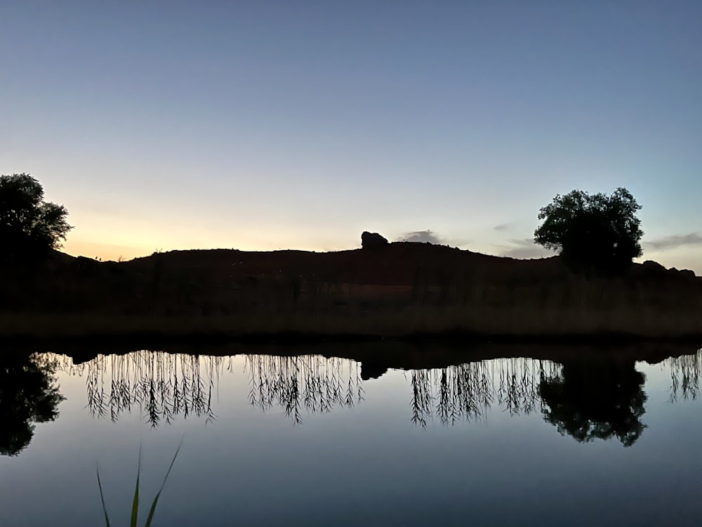 a body of water with a hill in the background