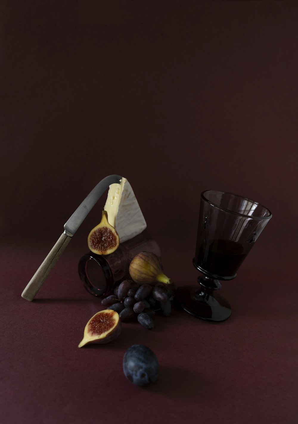 a still life of figurines, a knife, and a glass of wine