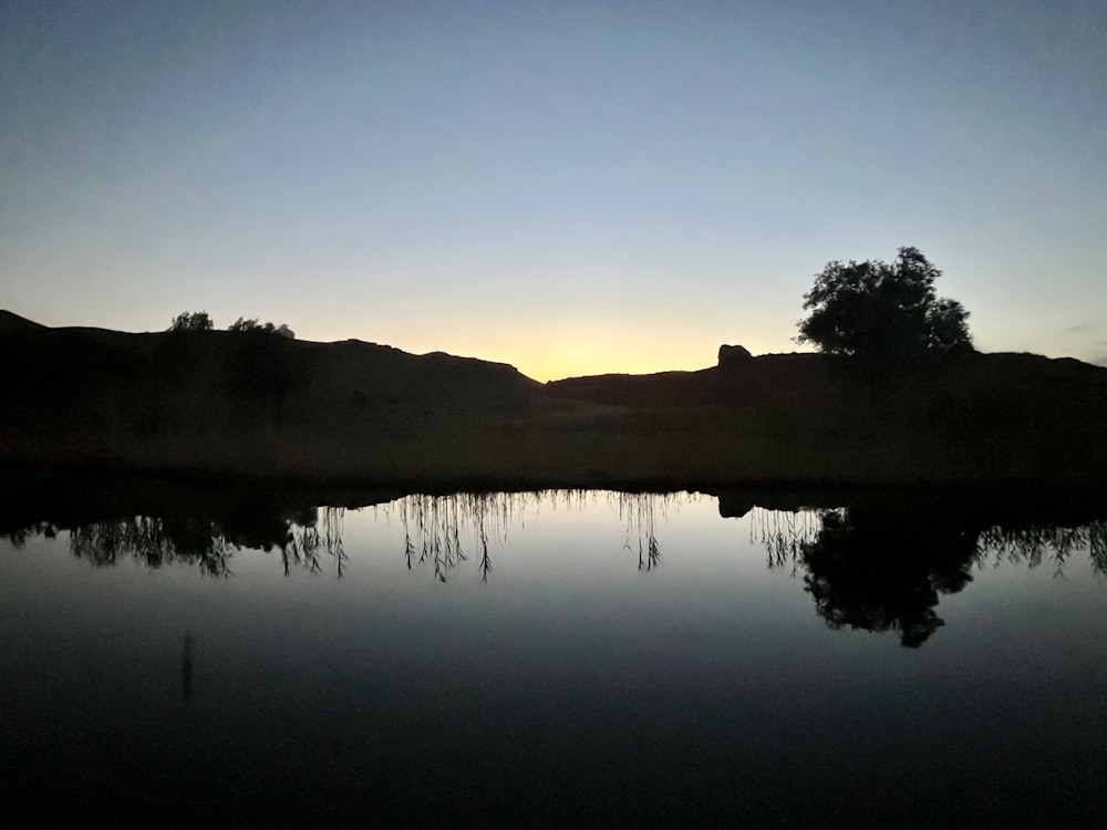 a body of water with a hill in the background