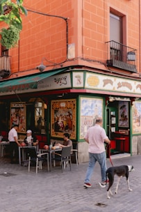 a man walking a dog in front of a restaurant