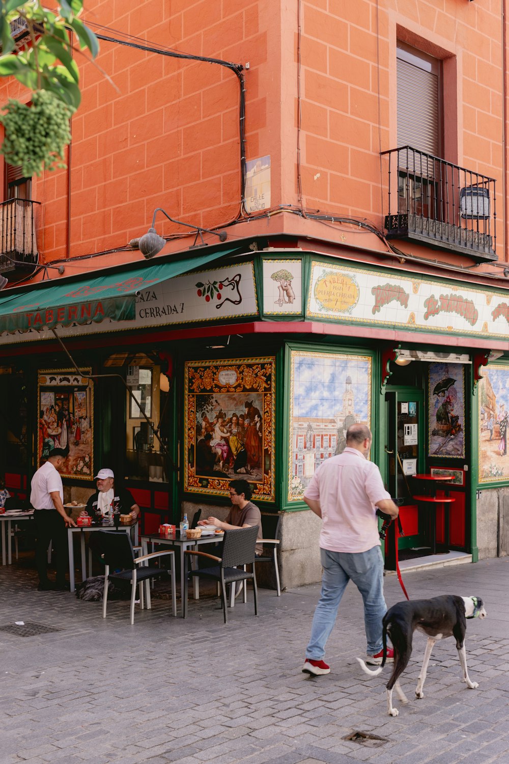 a man walking a dog in front of a restaurant