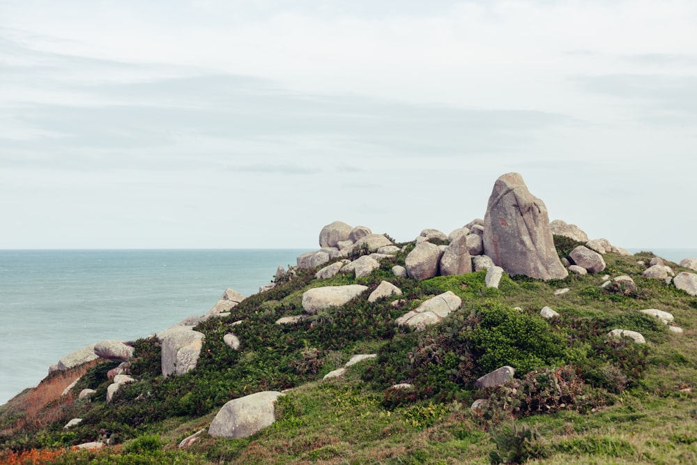 a large rock formation on a grassy hill by the ocean