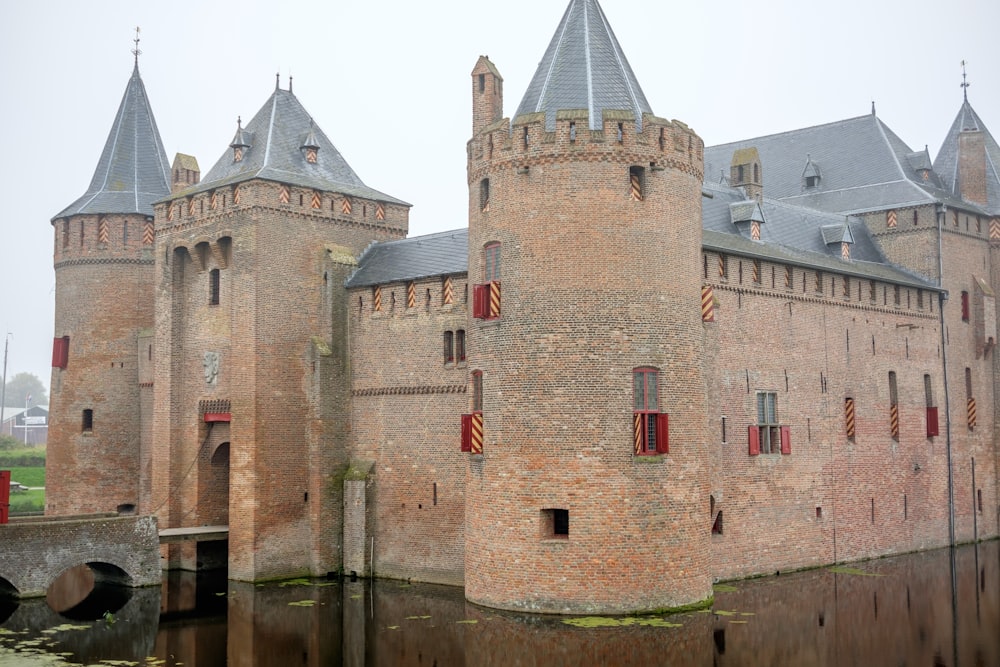Un gran castillo con dos torres junto a un cuerpo de agua