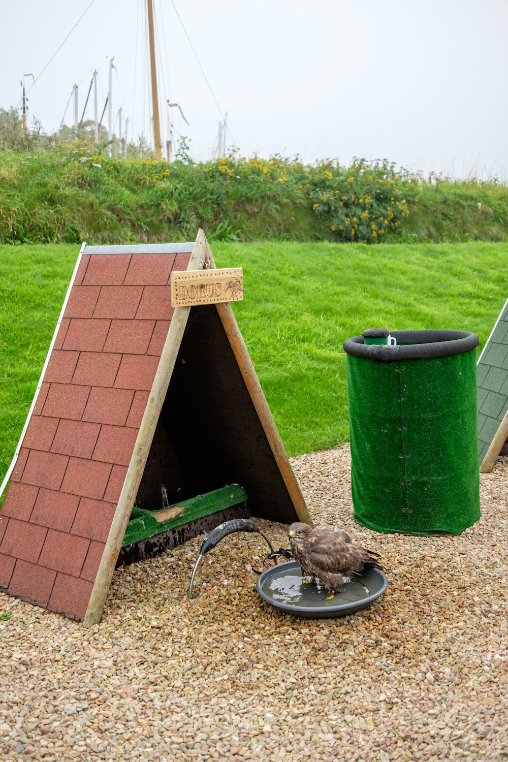 a green trash can sitting next to a red brick building