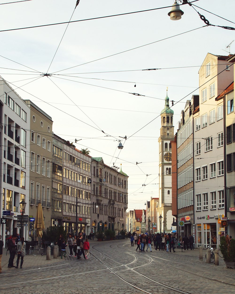 a group of people walking down a street next to tall buildings