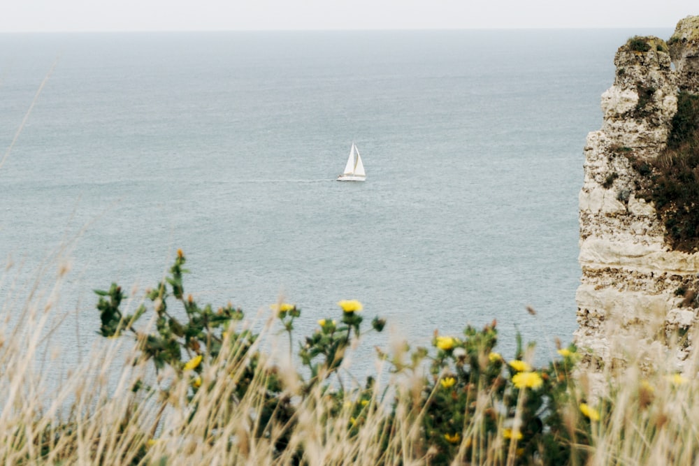 a sailboat is out on the water near a cliff