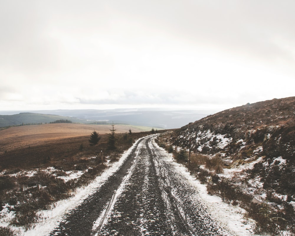 a dirt road in the middle of a snowy field