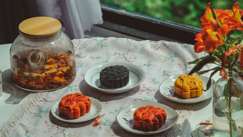 a table topped with plates of food next to a vase filled with flowers