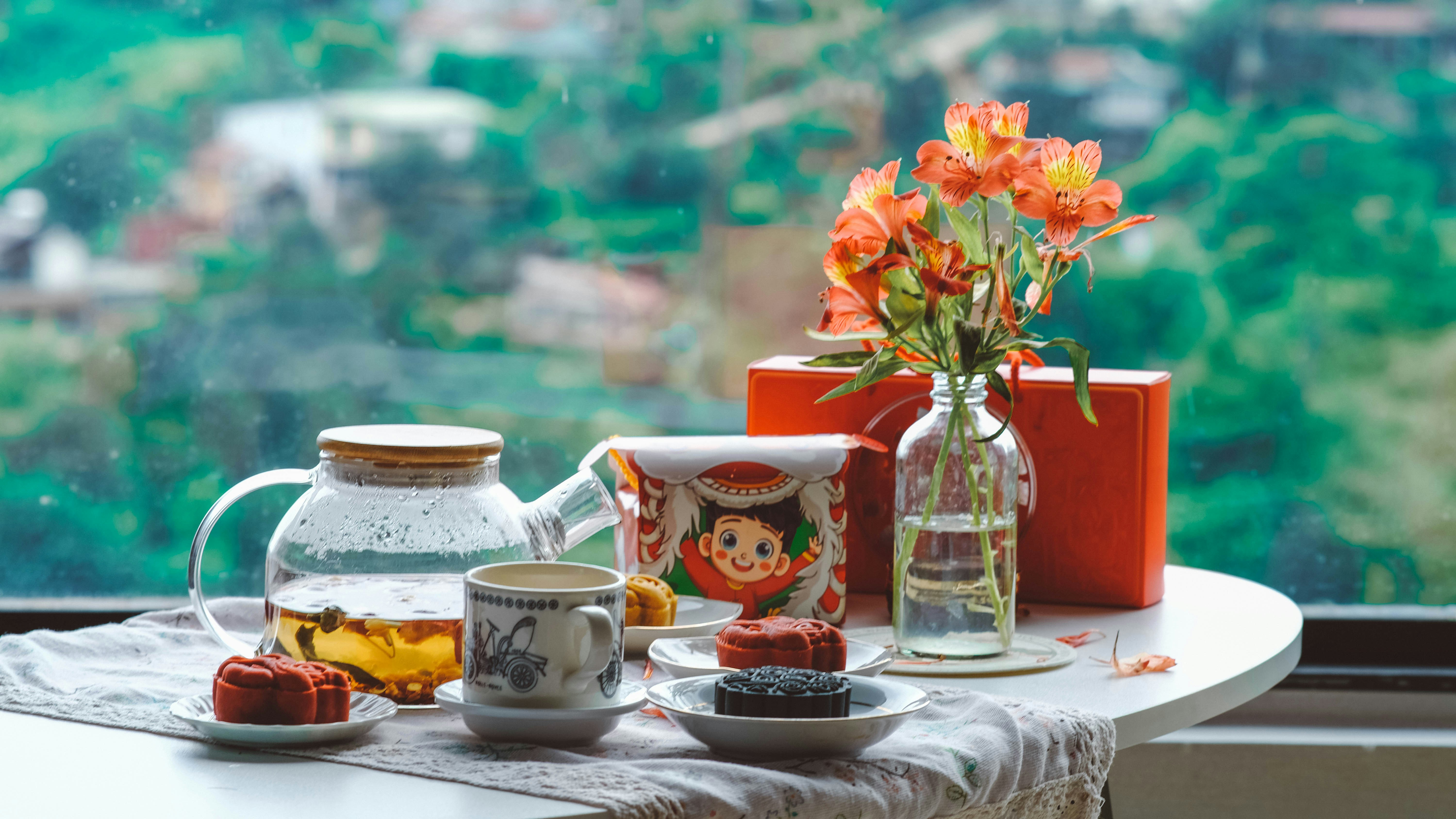 a table with a vase of flowers and tea on it, mooncakes with tea pot