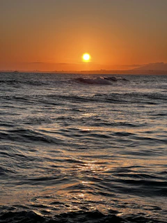 A serene sunset over a calm ocean with warm golden and deep blue hues.