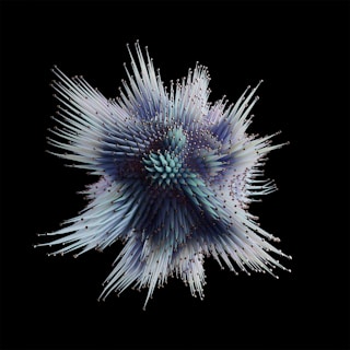 A complex geometric structure with spiky protrusions emerges against a black background. The spikes are multicolored, predominantly featuring shades of blue, purple, and teal. The structure has an organic and symmetrical appearance, resembling a sea urchin or an abstract starburst.