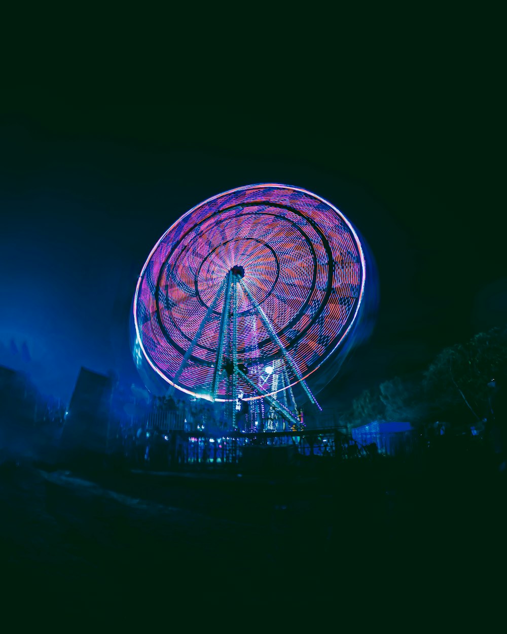 a ferris wheel lit up at night in the dark