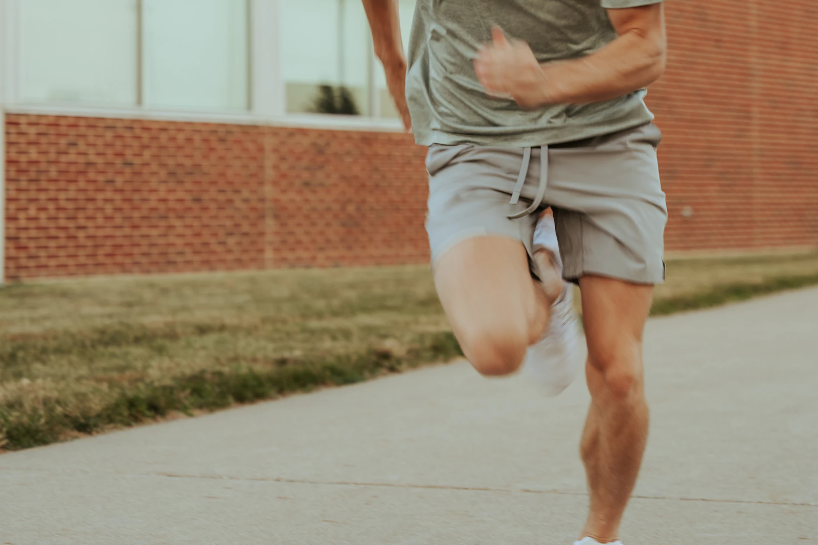 A man running down a pavement in front of a building