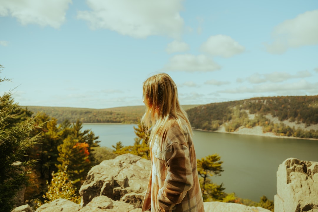 a woman standing on top of a mountain overlooking a lake,