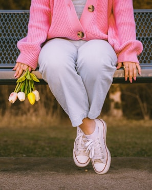 a woman sitting on a bench holding flowers
