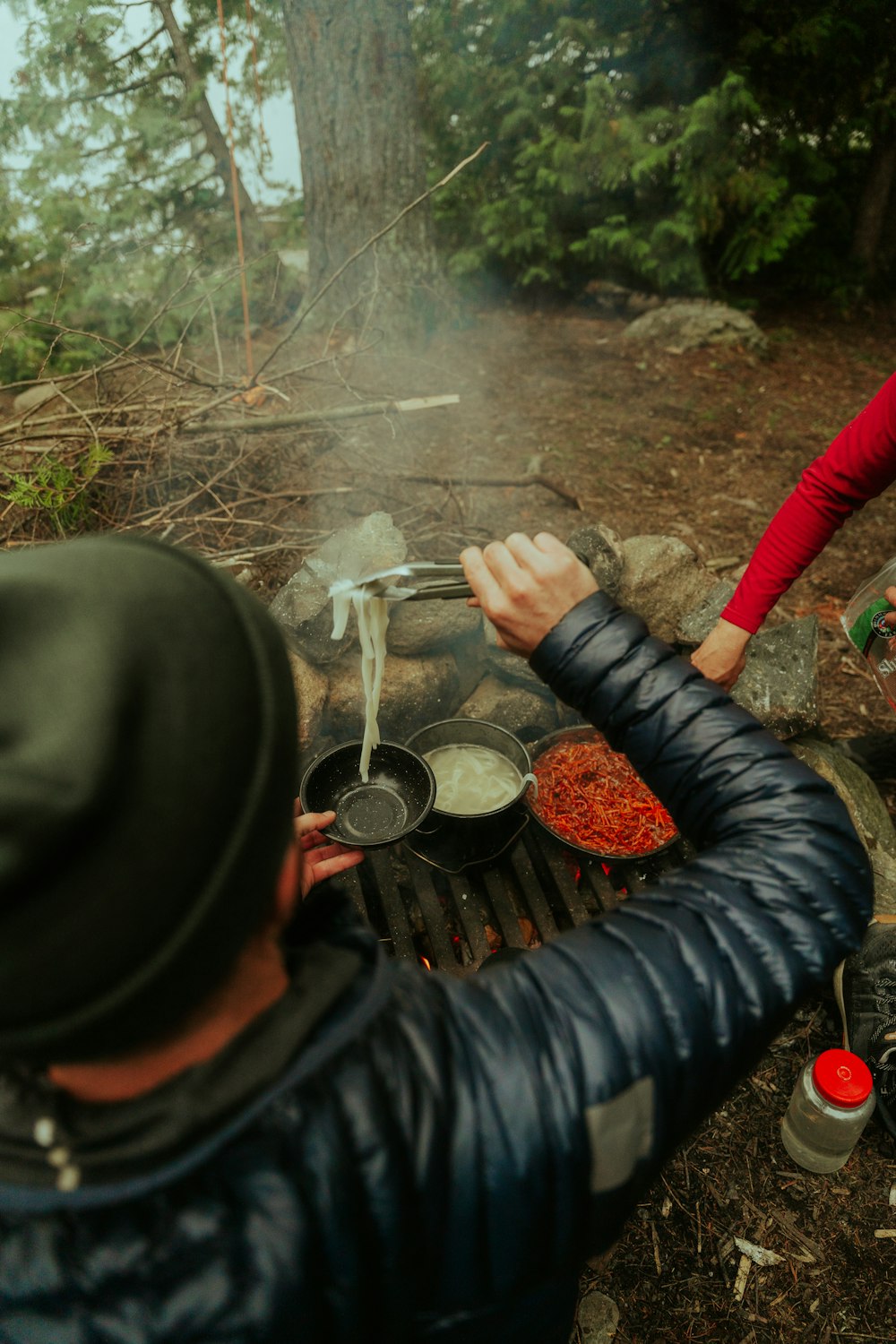 a man and a woman cooking over a campfire