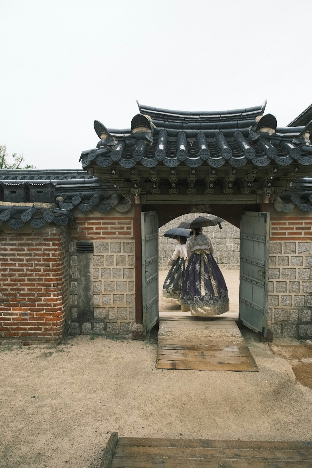 a woman with an umbrella walks through a gate