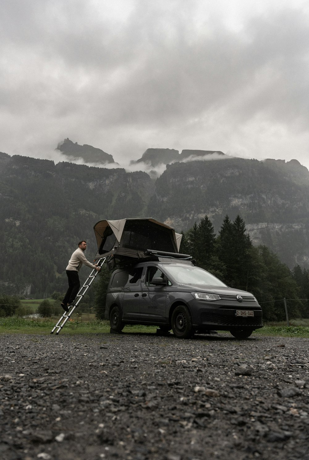 a van parked on a gravel road with a man standing next to it