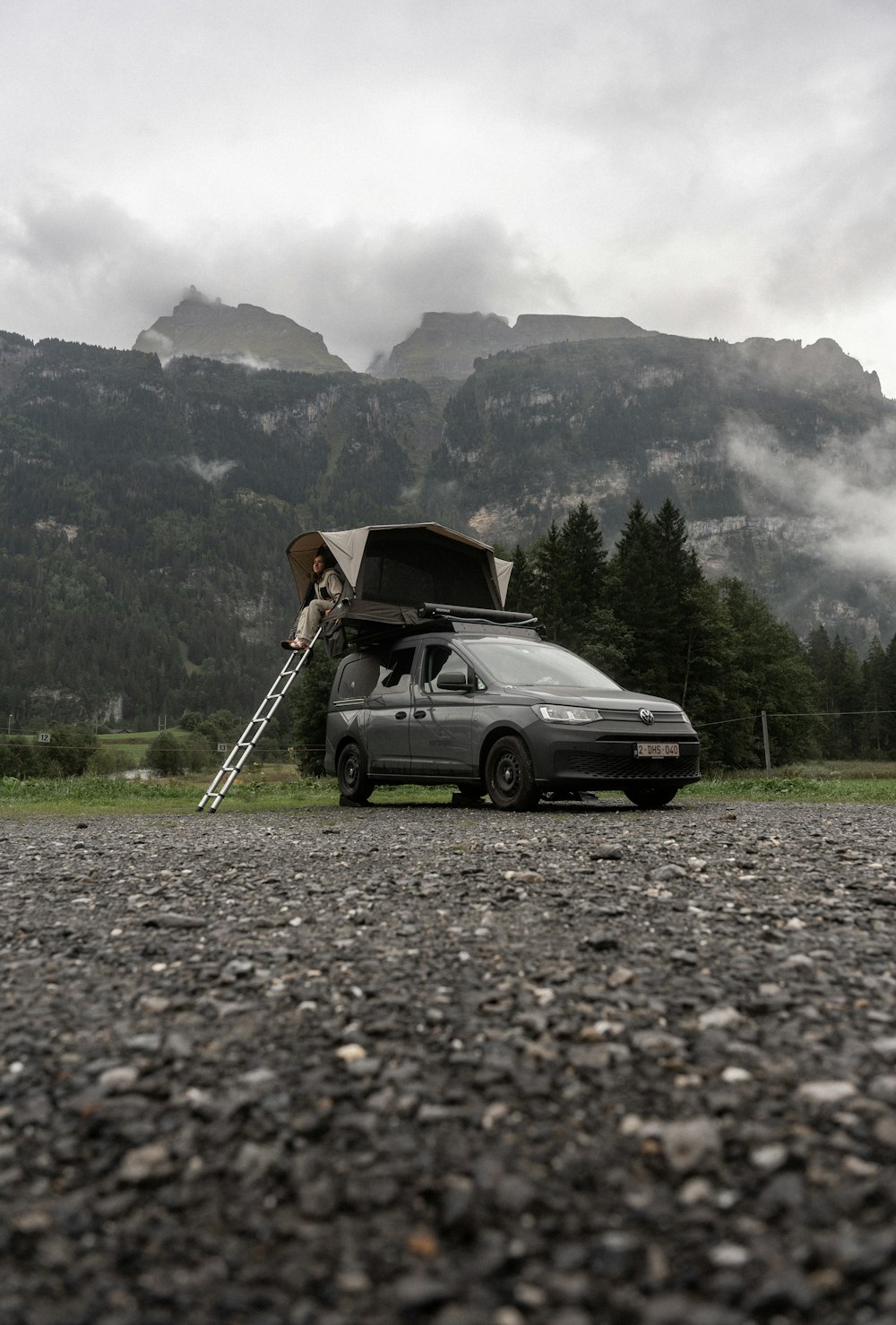 a van parked on a gravel road with a ladder up to it