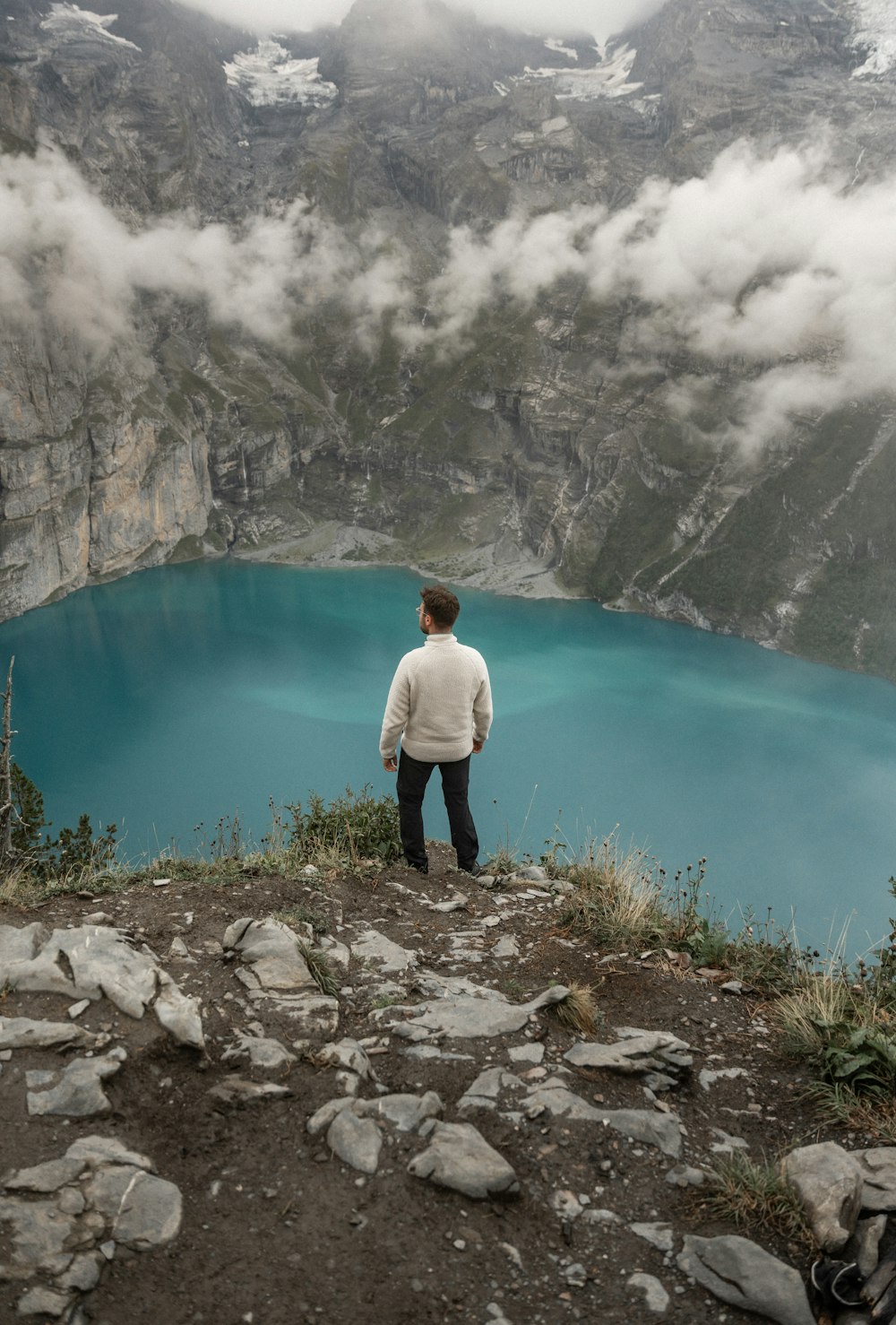 a man standing on top of a mountain next to a lake