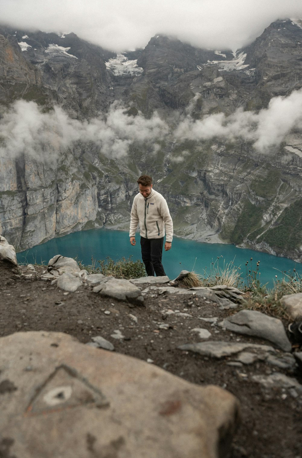 a man standing on top of a mountain next to a lake