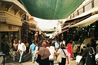 a group of people walking down a street next to shops