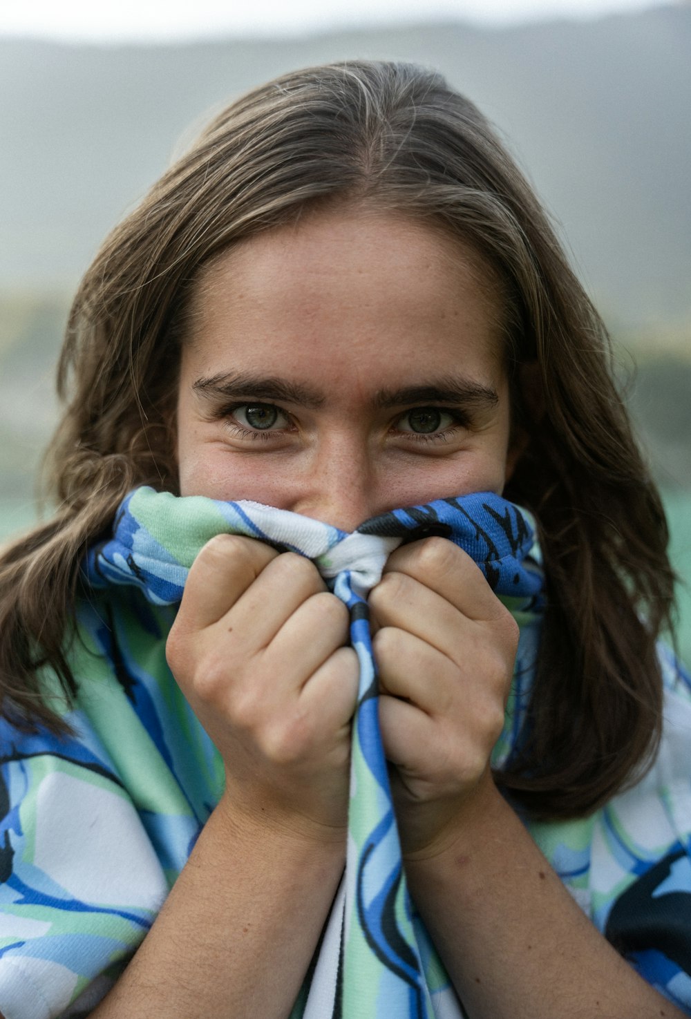 a woman covers her face with a scarf