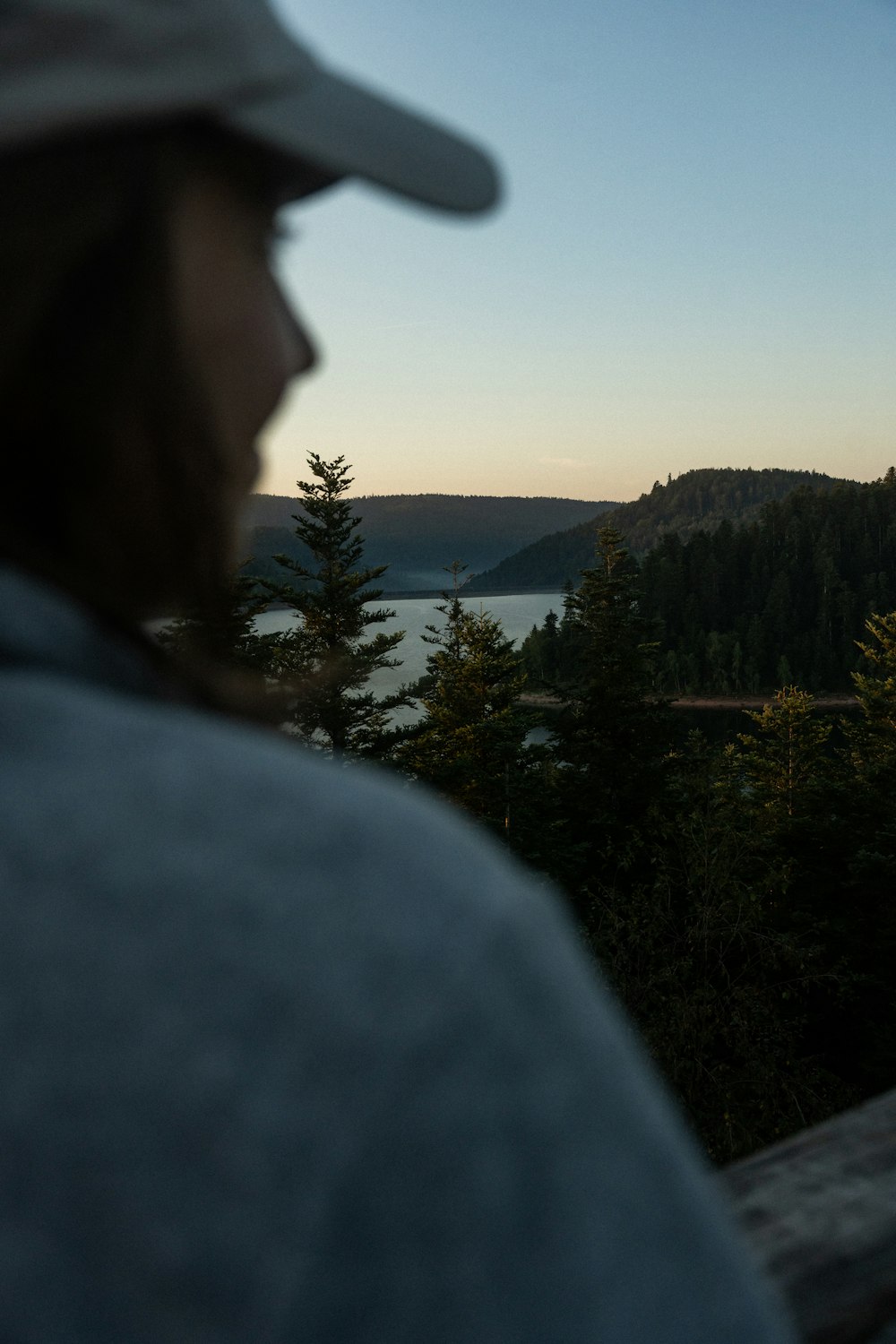 a man in a hat looking out over a lake