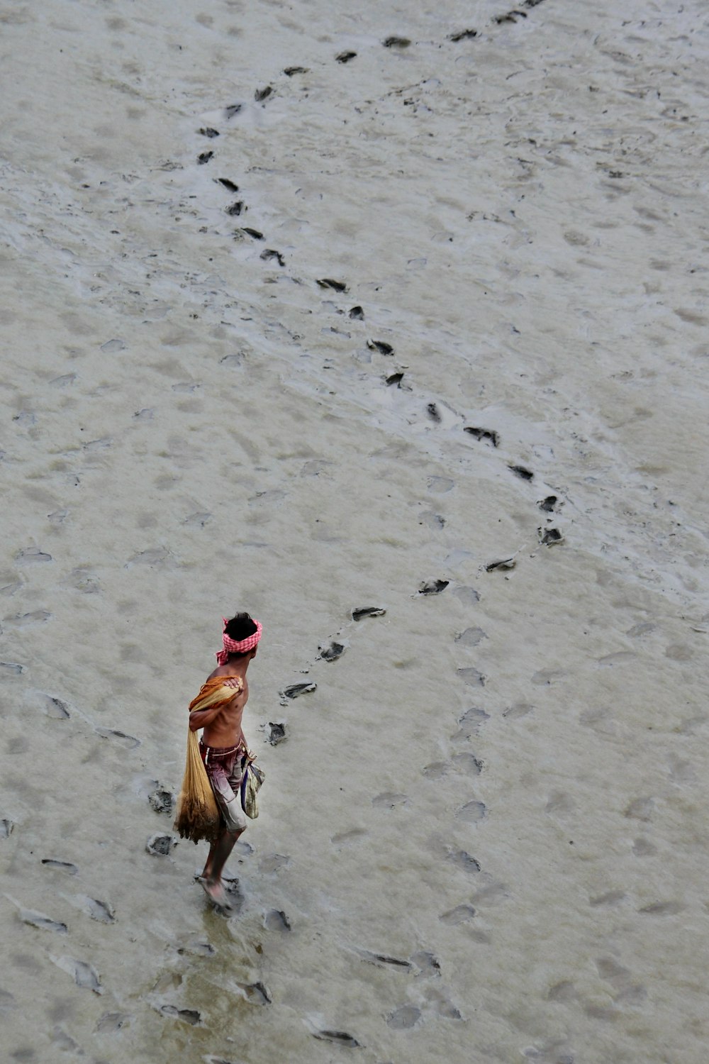 a woman walking across a sandy beach next to footprints