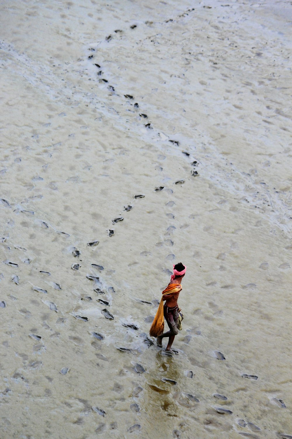 a person walking in the water with a hat on