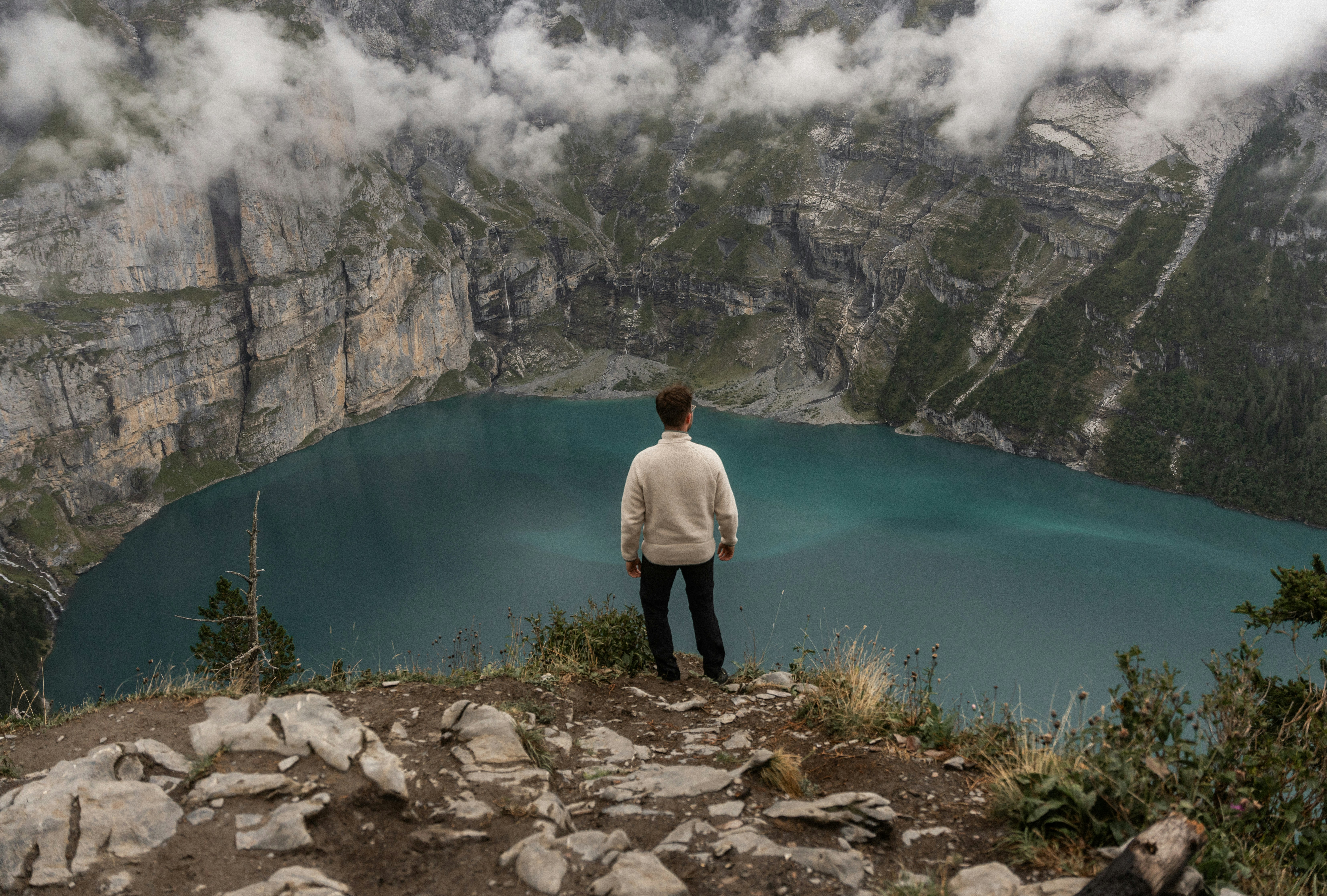 a man standing at the top of a mountain looking at a lake