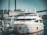 A luxurious white yacht docked at a marina, surrounded by industrial buildings and structures in the background. The yacht is equipped with various modern equipment and is stationed in calm waters.
