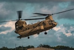 a large military helicopter flying through a cloudy sky